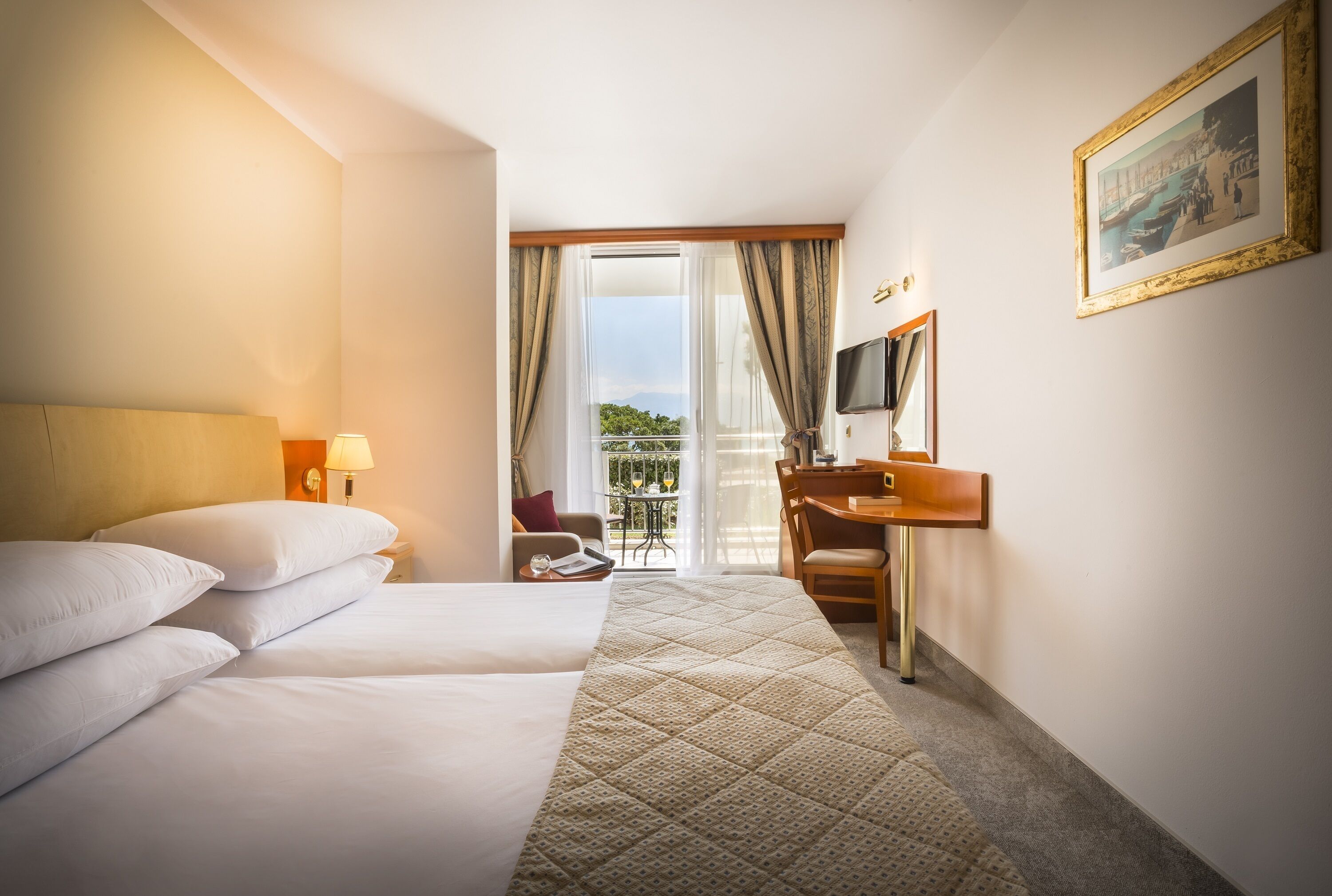 Habitación de hotel con dos camas, un escritorio, una silla, un televisor y un balcón con vistas.