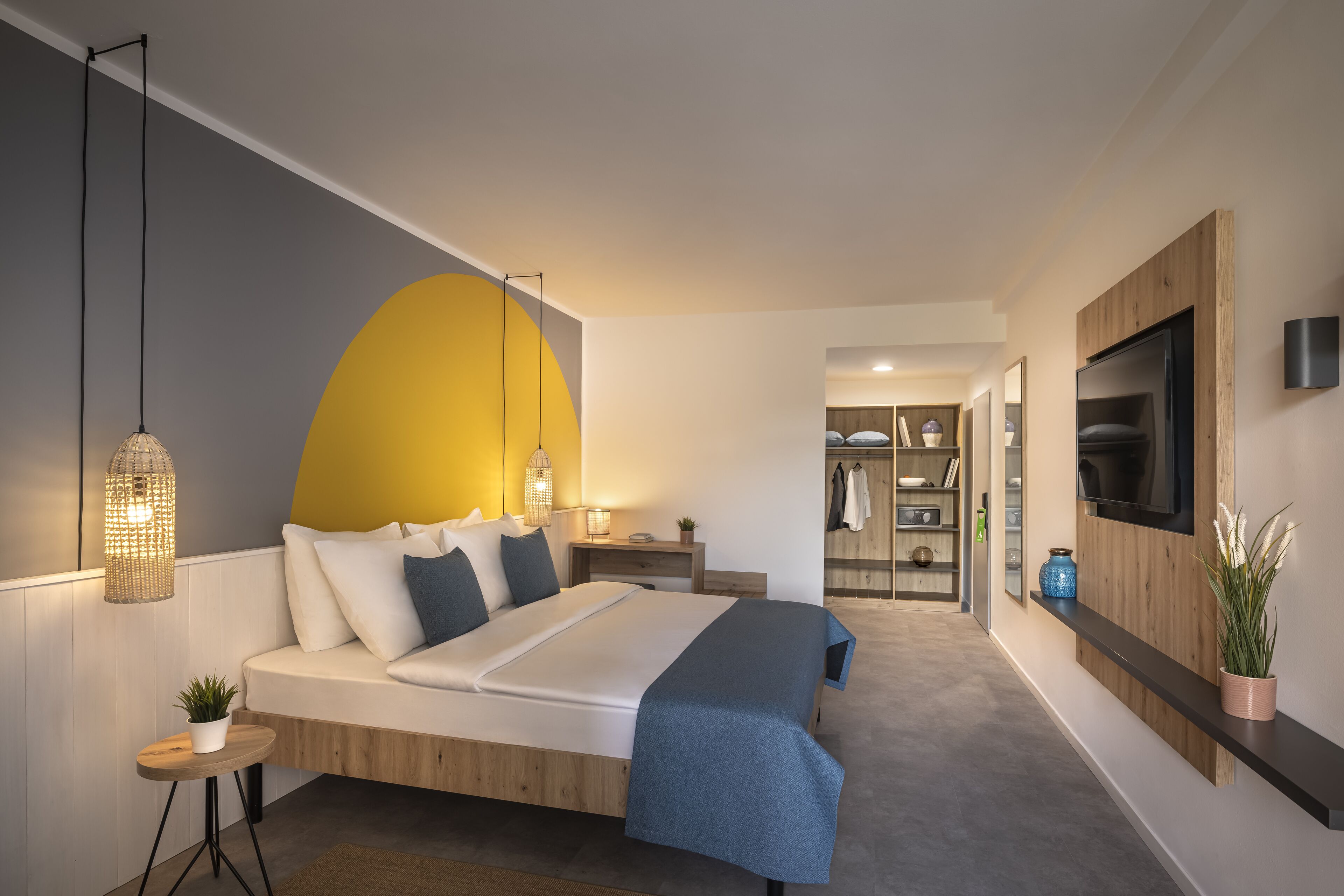 A modern bedroom with a bed, bedside tables, a TV, and a wardrobe.