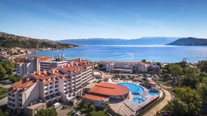 A hotel with multiple swimming pools, a large building with a red roof, and a view of the sea. - Sunny Baška Hotel by Valamar, ex Corinthia (Baska)