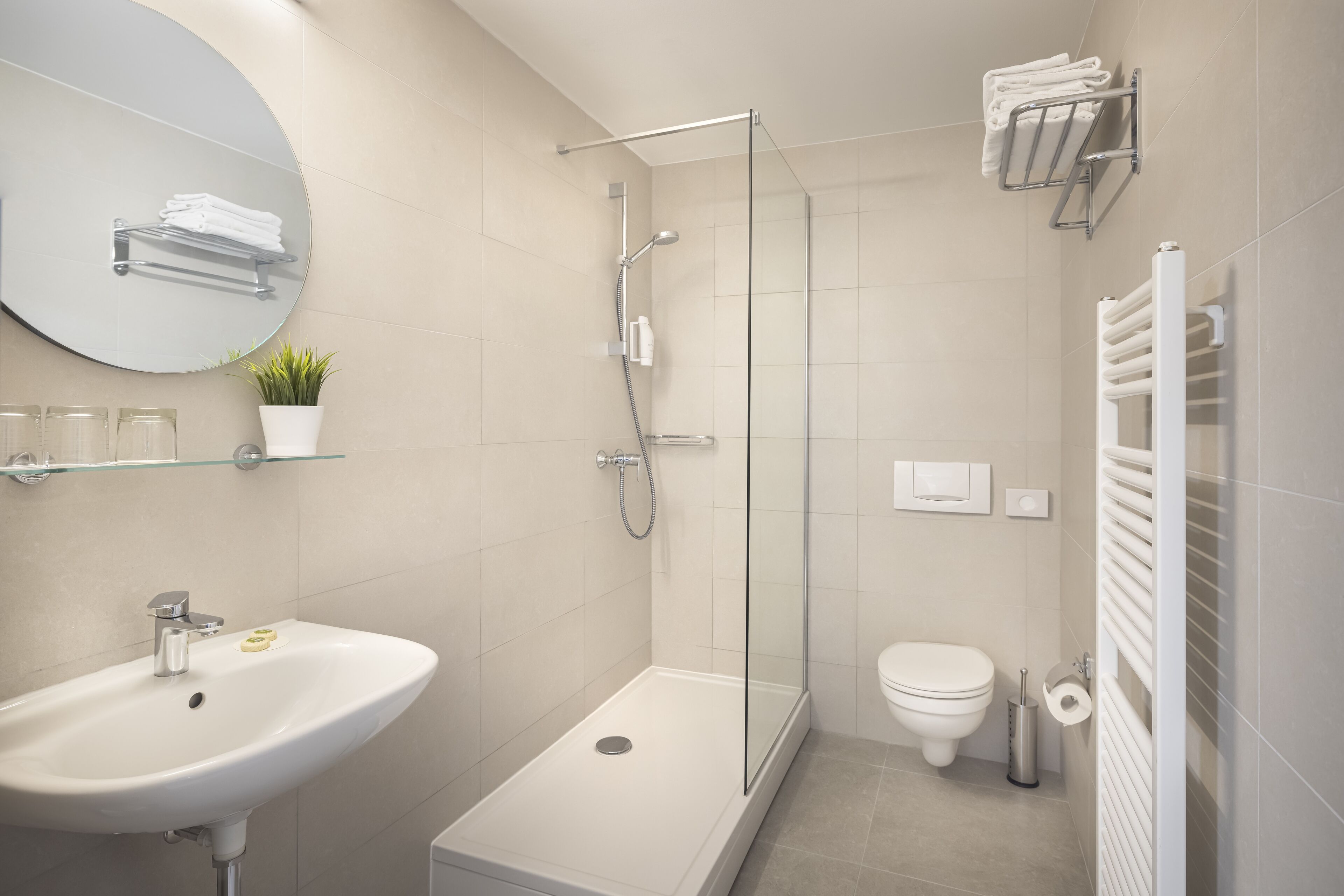 A modern bathroom with a shower, toilet, sink, and a mirror.