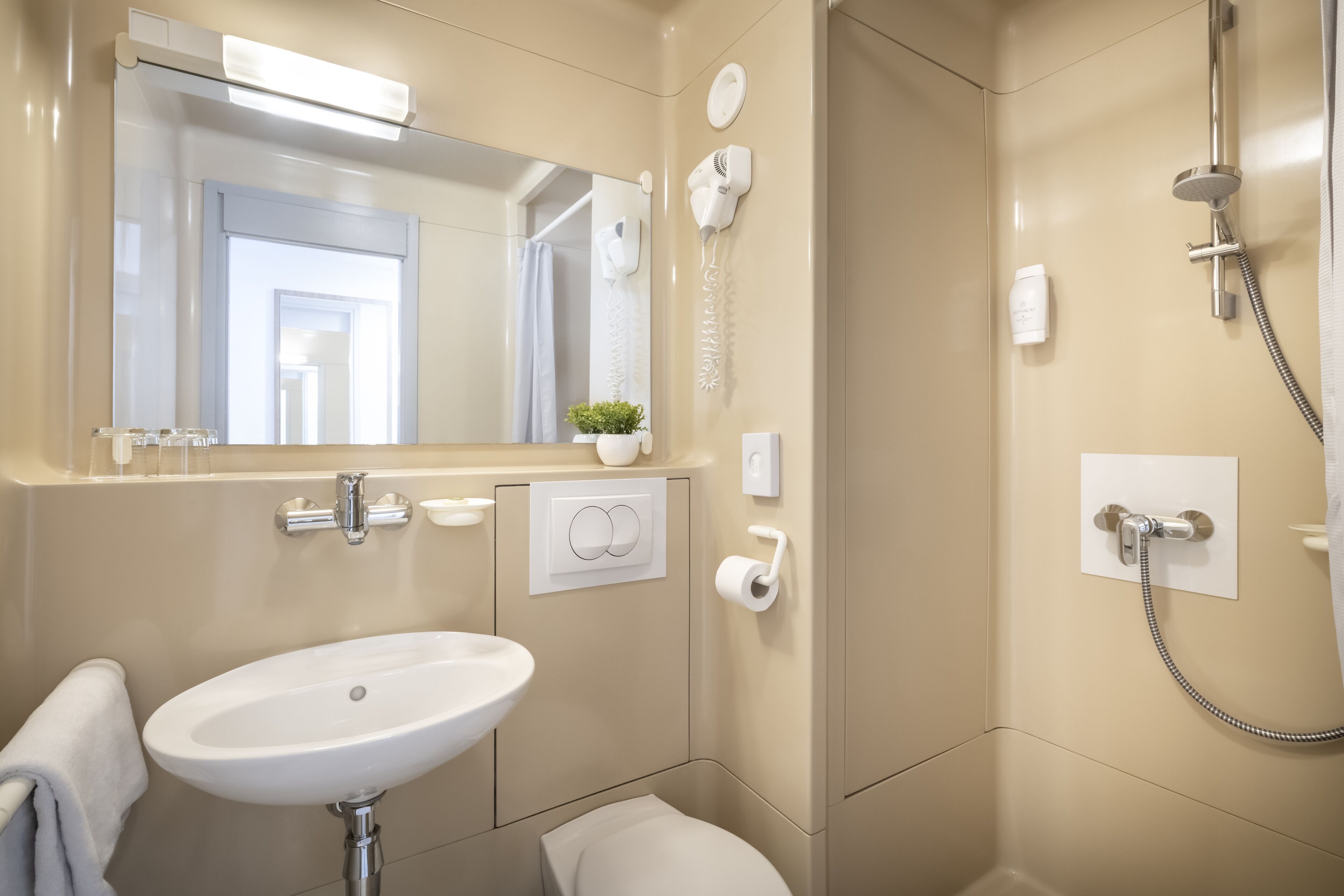 Un baño moderno con lavamanos, espejo, toallero, ducha y secador de pelo.