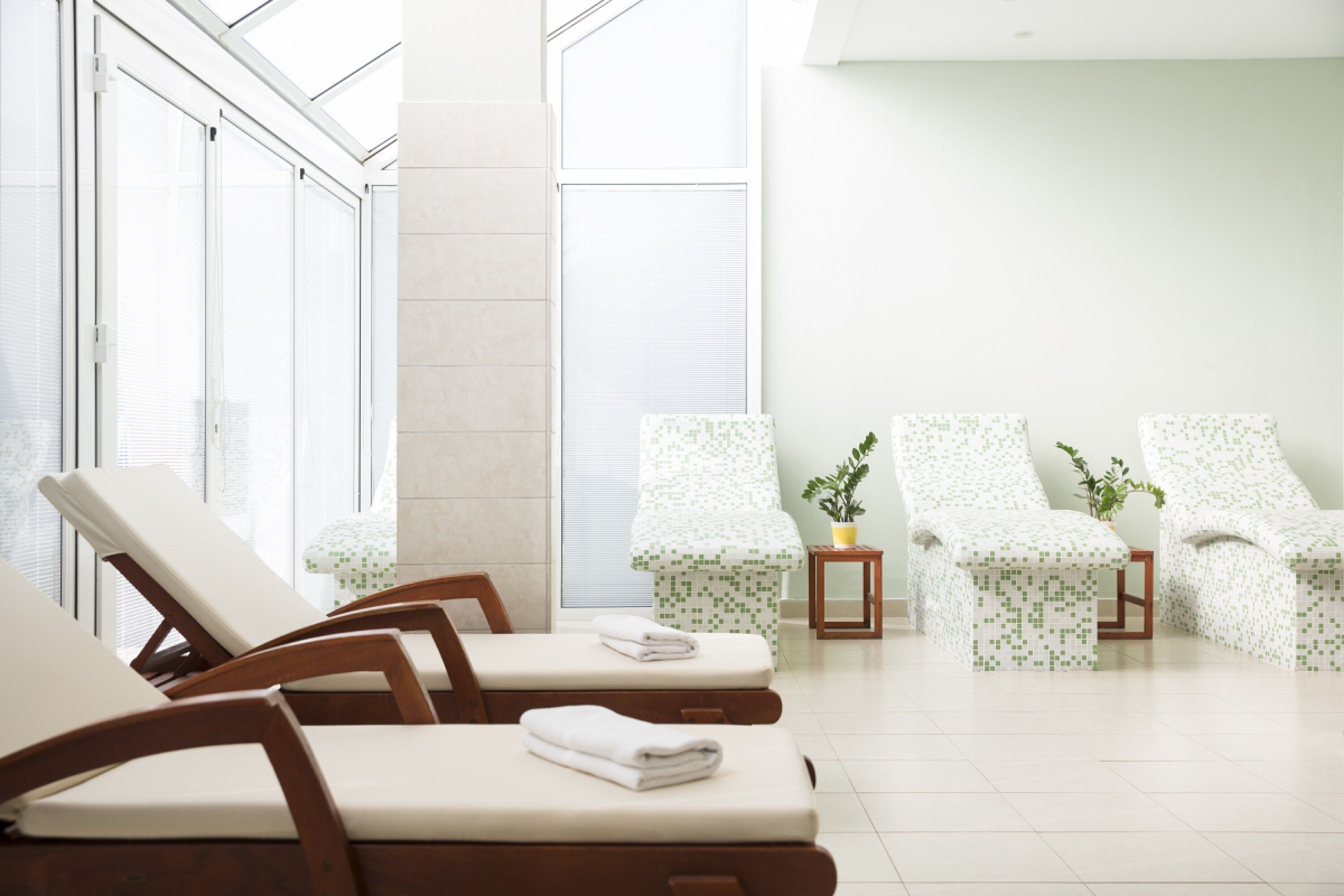Sala de spa com cadeiras de madeira e uma pequena mesa com uma planta.