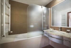 Un baño moderno con ducha de vidrio, una bañera y un tocador con lavamanos y espejo.