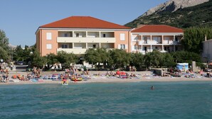 A beachfront hotel with multiple balconies, a sandy beach, and a mountain in the background.