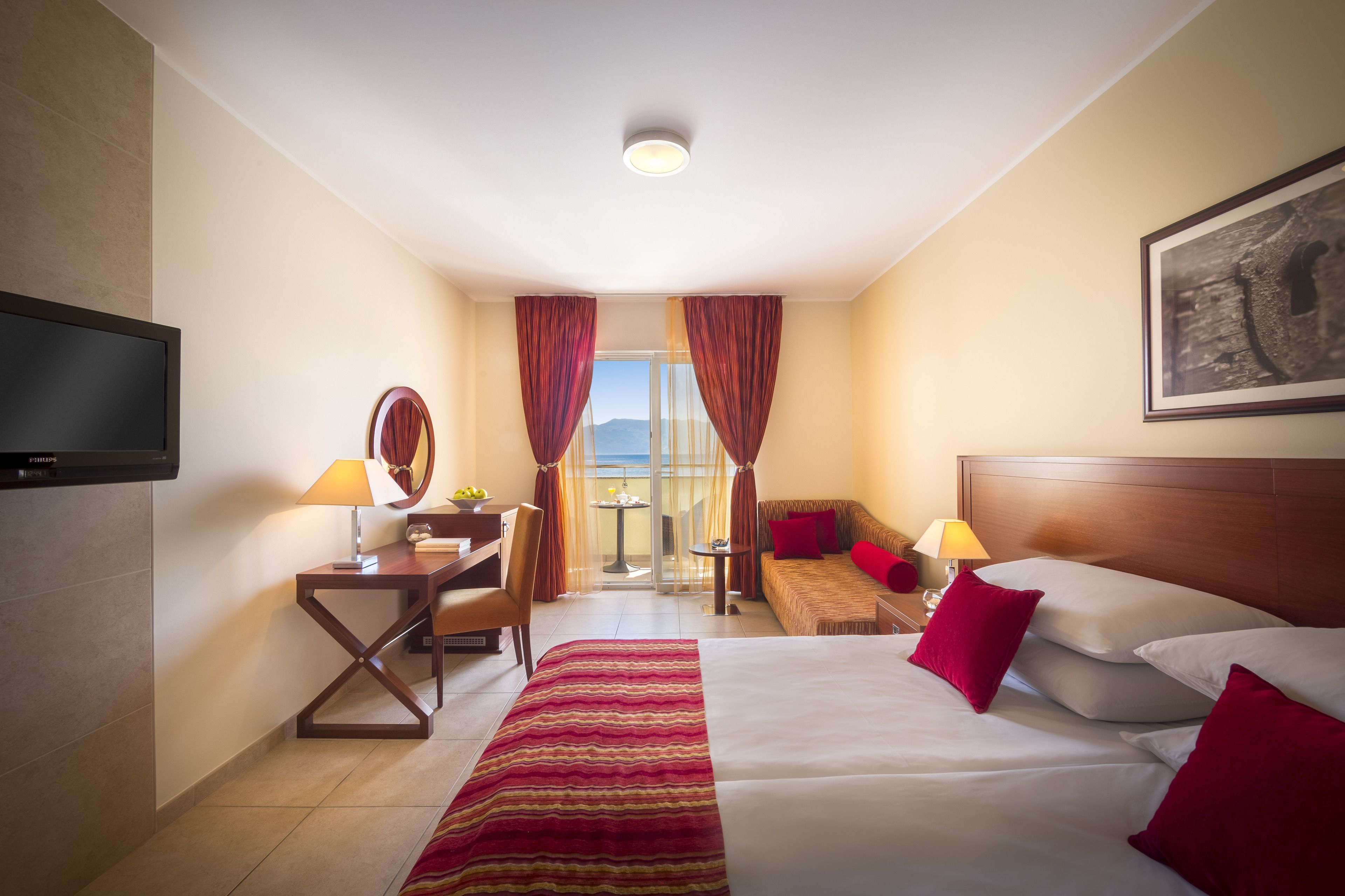Una habitación de hotel con cama, escritorio, silla y televisor.