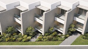 Un edificio moderno con varios balcones, techo plano y un jardín ajardinado.