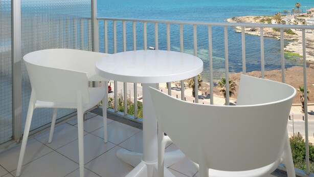 A balcony with a white table and chairs, overlooking a coastal view with clear skies. - BQ Apolo Hotel (Palma de Mallorca)