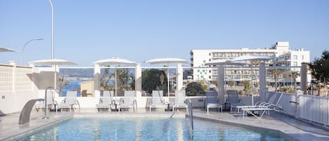 Una piscina techada, una piscina al aire libre, sombrillas