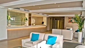 A modern living room with white sofas, a glass coffee table, and a reception desk. - BQ Apolo Hotel (Palma de Mallorca)