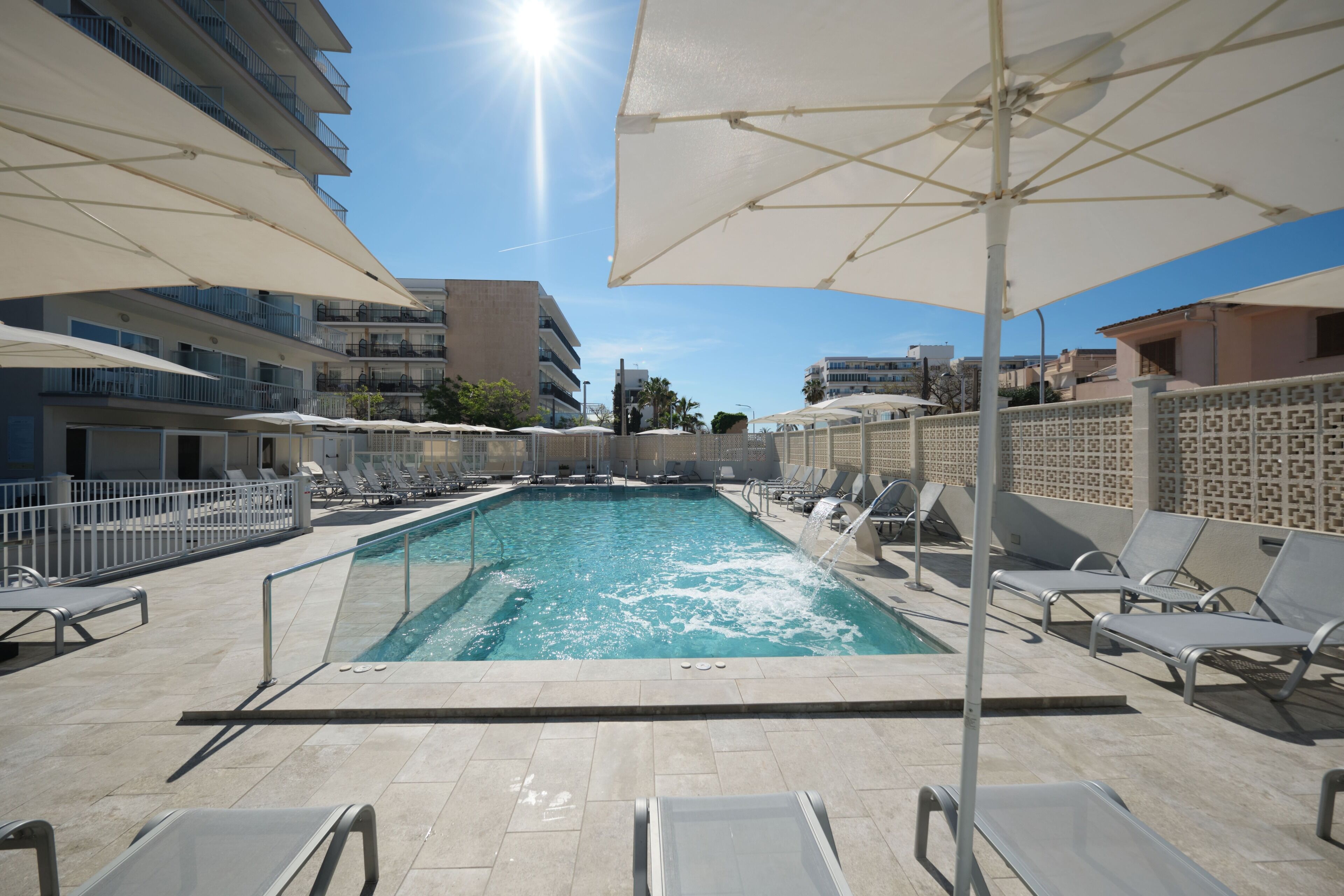 Une piscine dotée de parasols, de chaises longues et d’une terrasse carrelée.