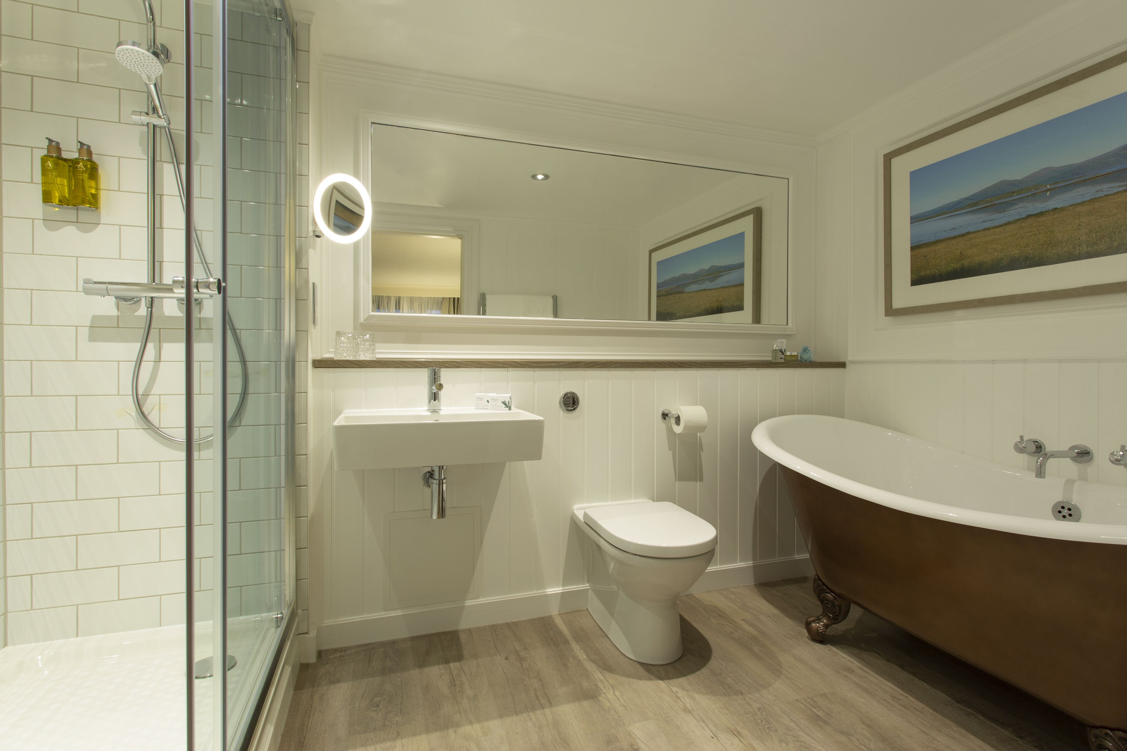 Un baño moderno con cabina de ducha de vidrio, inodoro independiente, lavamanos pedestal y una bañera clásica tipo pata de león.