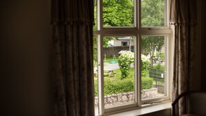 A room with a large window, curtains, and a chair.