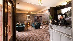A lobby with a checkered floor, a fireplace, and a reception desk. - Balmoral Arms (Ballater)