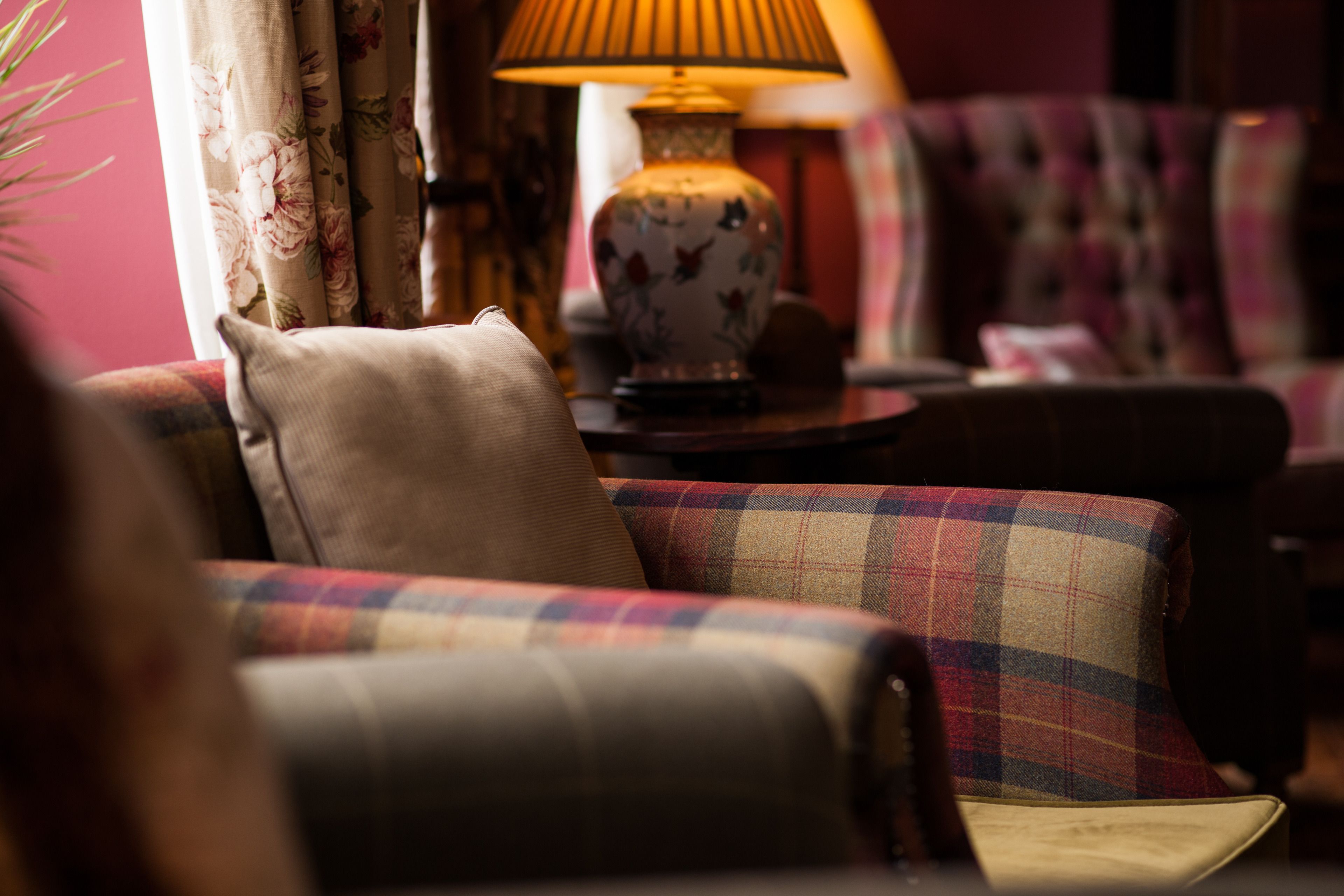 A cozy living room with a sofa, a patterned armchair, and a table with a lamp.
