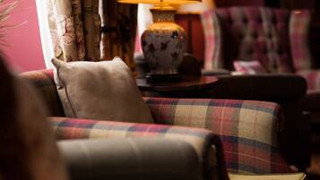 A cozy living room with a sofa, a patterned armchair, and a table with a lamp.