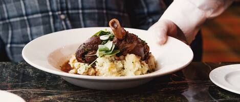 A plate of food with mashed potatoes and a piece of meat, possibly lamb, garnished with greens.