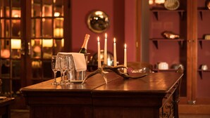A bar area with a wooden counter, glasses, a bottle, and candles.