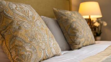 A bed with patterned pillows and a lamp in the background.
