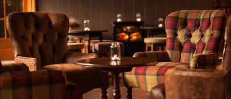 A cozy seating area with a round wooden table, two upholstered chairs, and a plaid-patterned sofa.