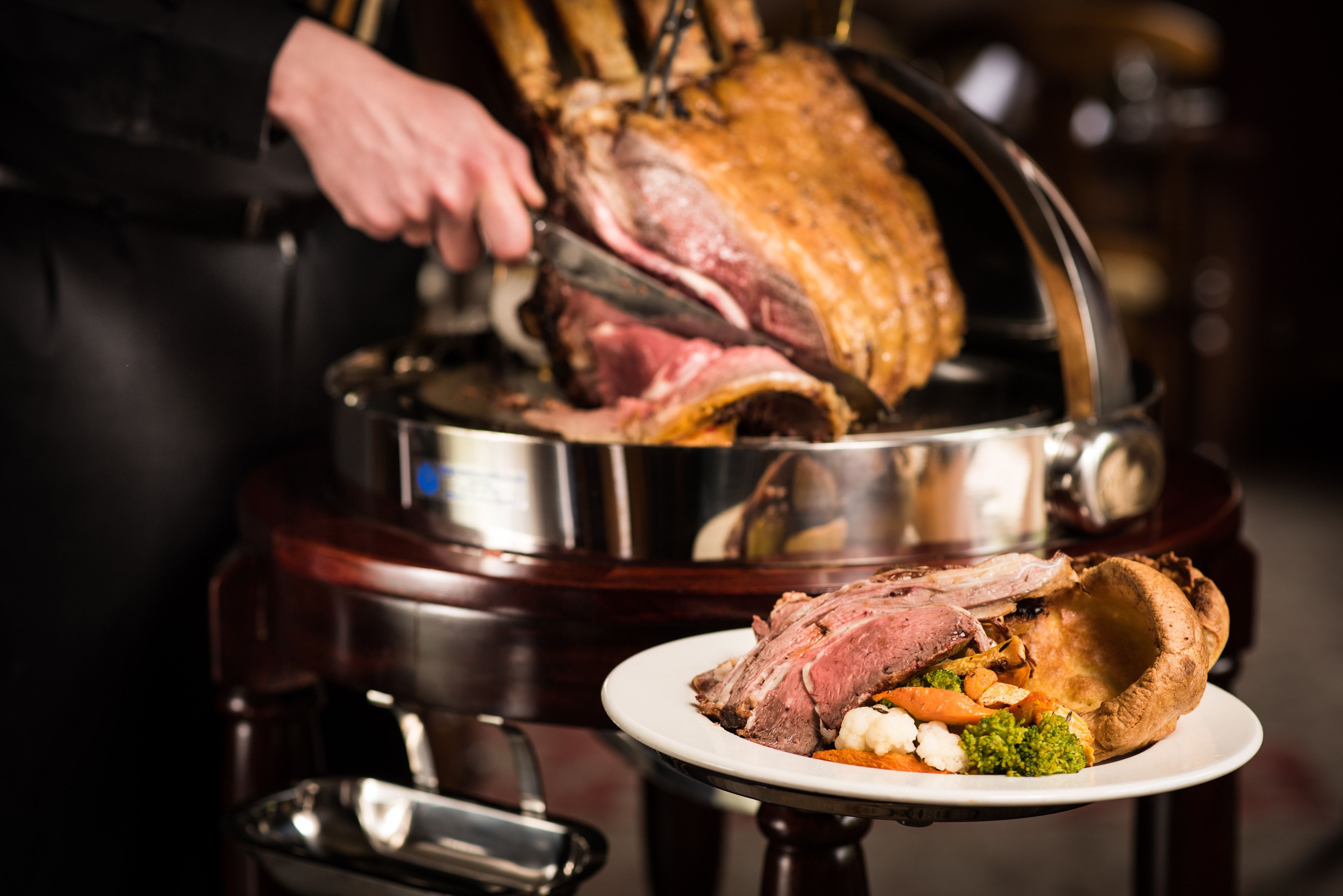 A roasted meat dish on a serving platter with a side of vegetables.