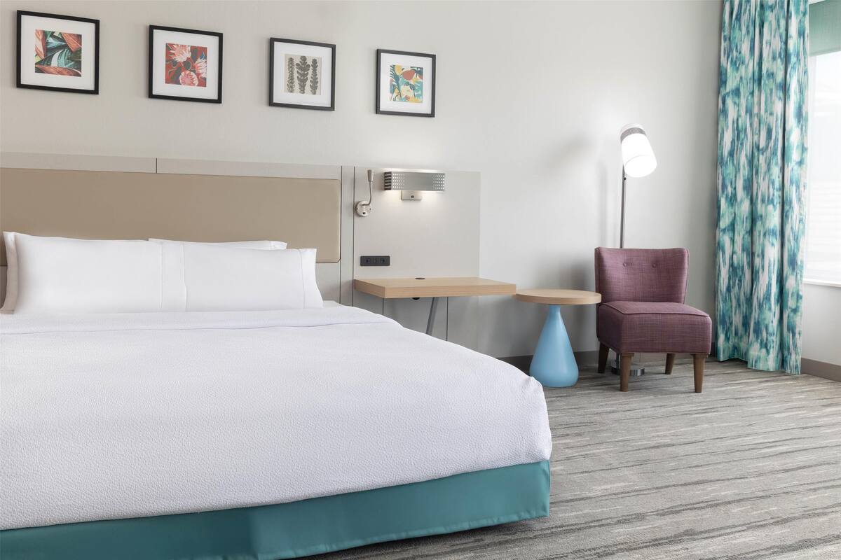 Een hotelkamer met een groot bed, een bureau, een stoel en een wandlamp.