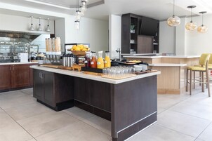 Una cocina moderna con una isla central, equipada con diversos electrodomésticos y una barra desayunadora.