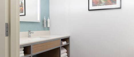 Un baño moderno con un lavamanos blanco, tocador de madera y un cuadro en la pared.