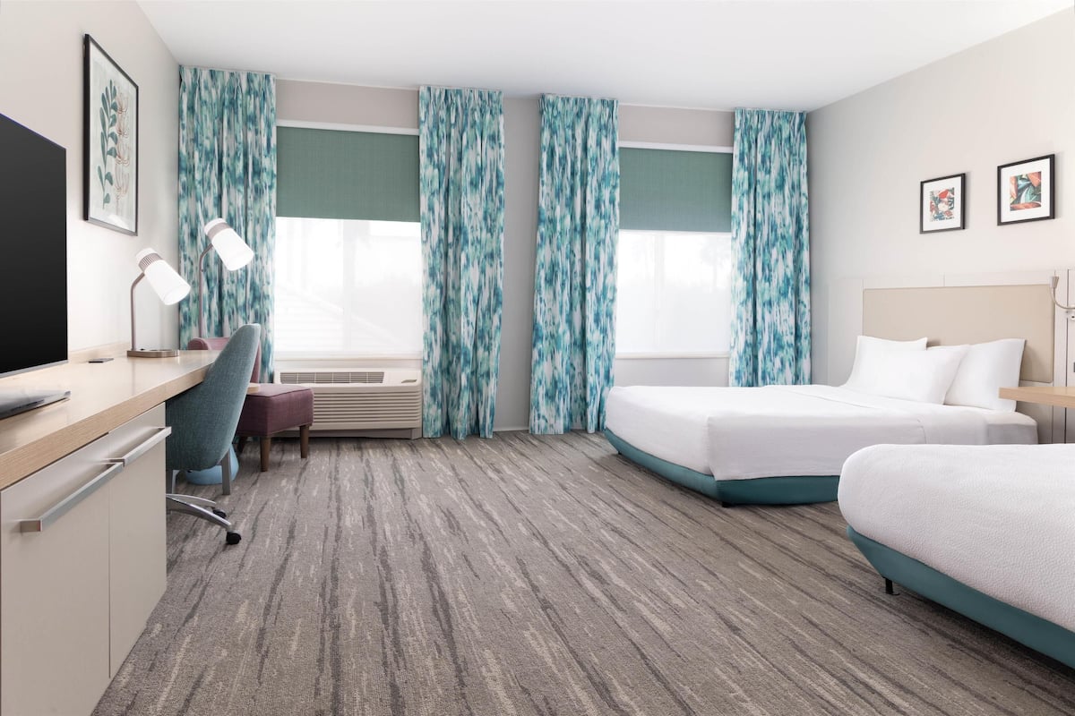 Een hotelkamer met een bed, bureau, stoel en televisie.