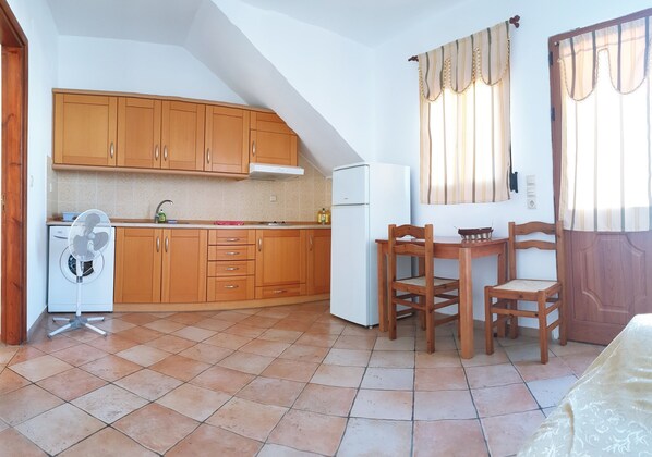 A compact kitchen with wooden cabinets, a built-in oven, and a small refrigerator.