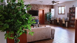 Una sala de estar con un sofá, un televisor, una estantería y una planta en maceta.