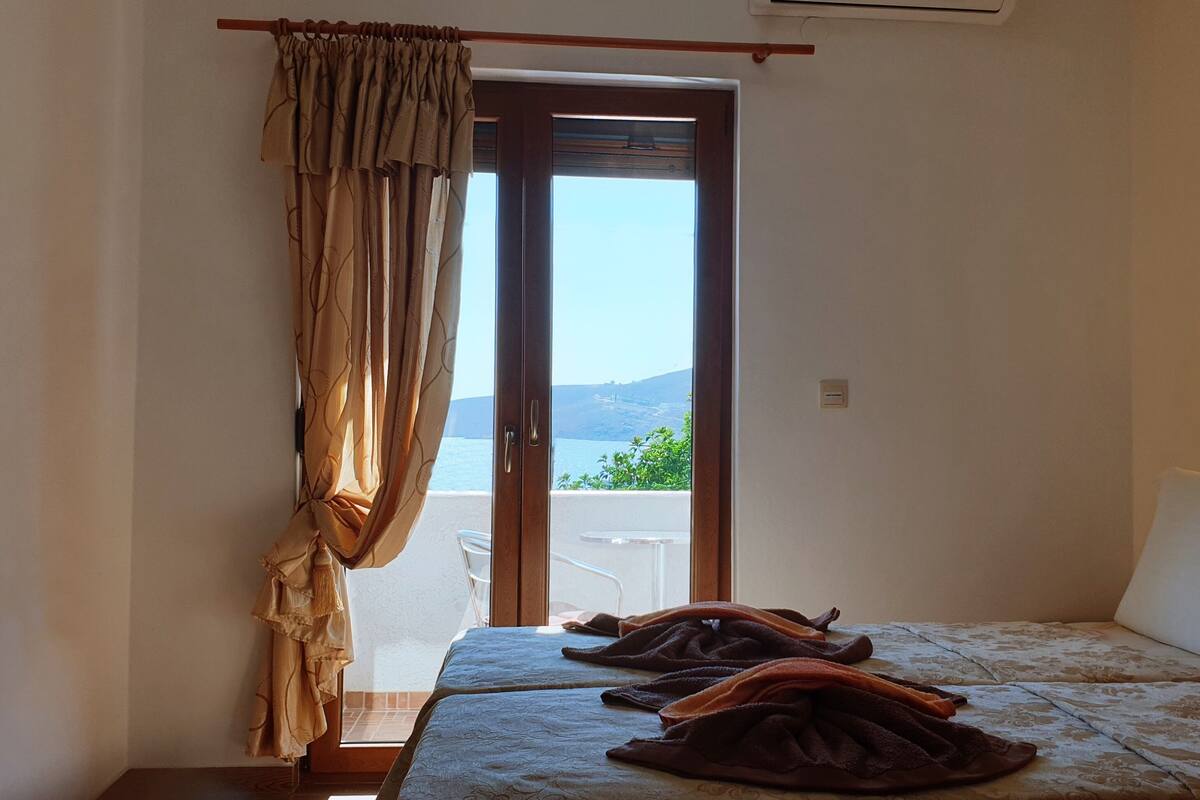 Un cuarto de hotel con una cama, vista al mar y un cuadro en la pared.