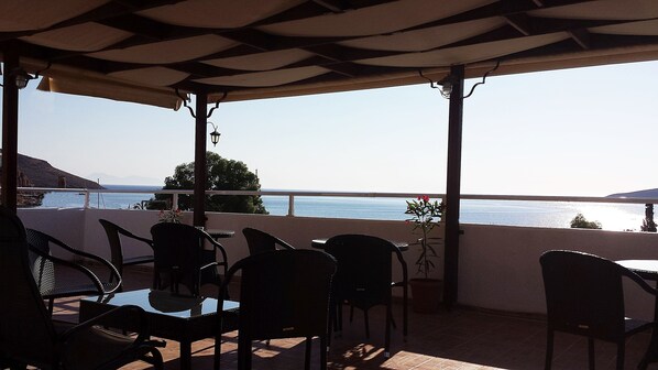 A terrace with a table and chairs, overlooking a body of water and distant land.