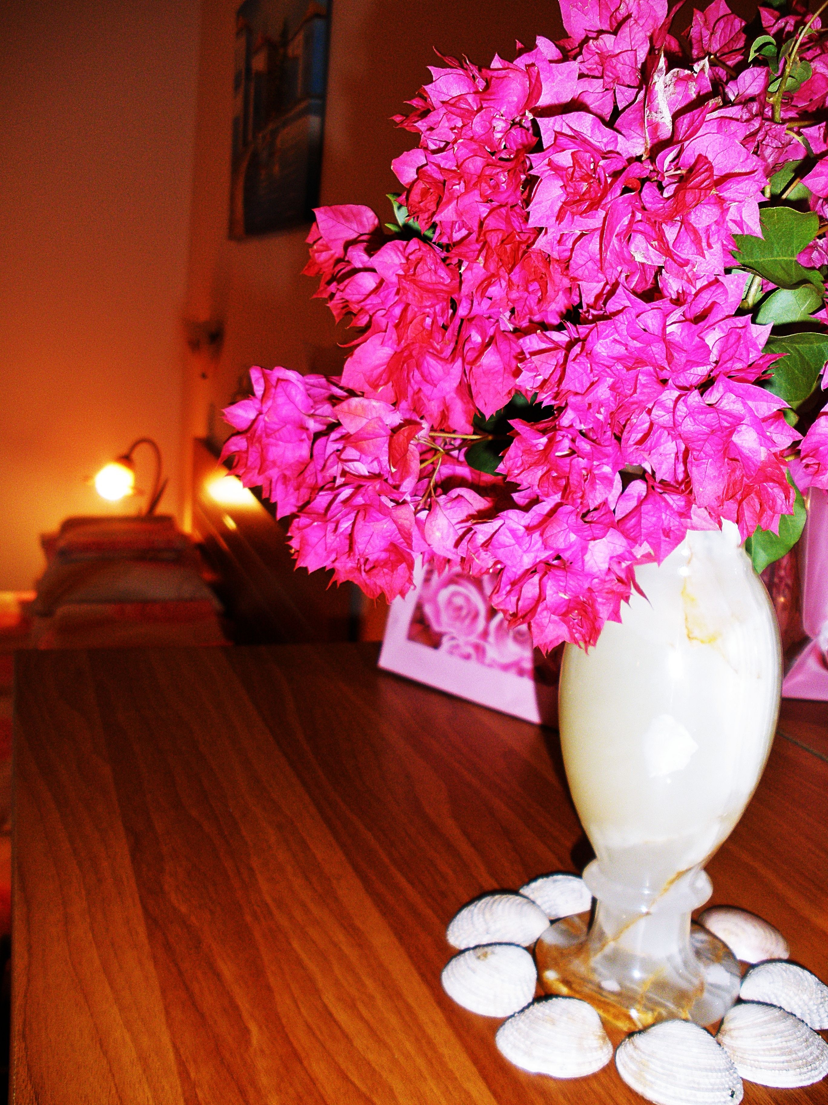 Un vase blanc orné de fleurs roses, posé sur une table en bois.