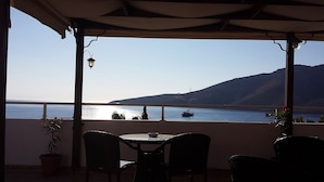 Una terraza con vista al mar y a la montaña, con una mesa y sillas.