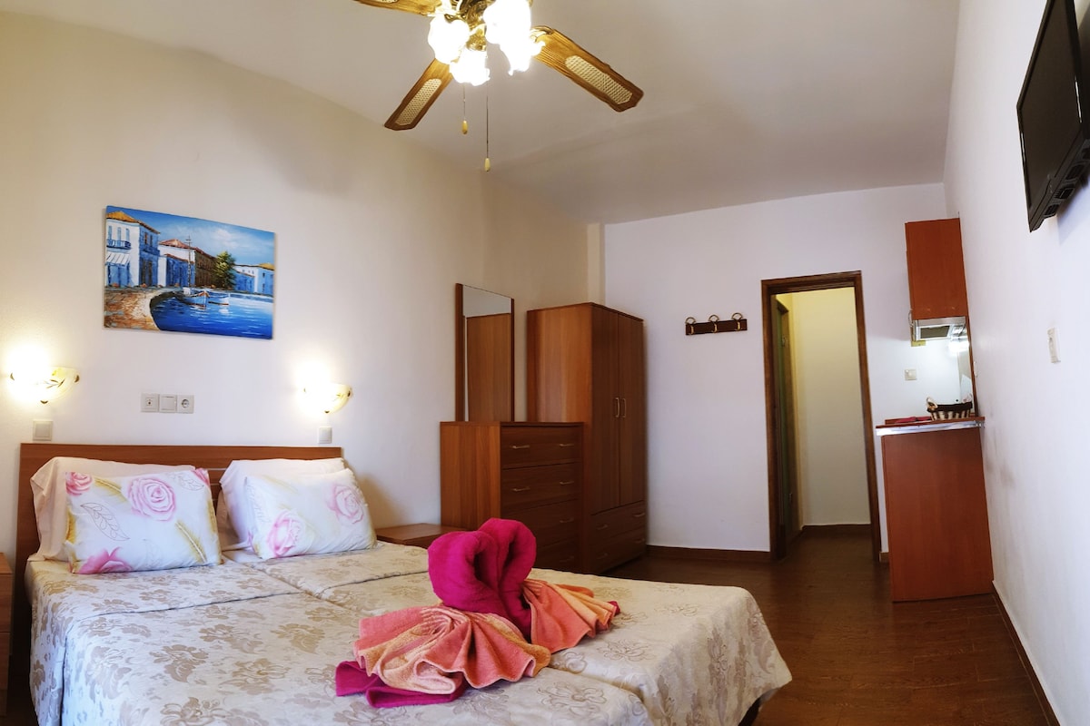 A hotel room with a bed, a painting, a wardrobe, and a bathroom visible through an open door.