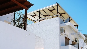 Un edificio de varios pisos con fachada blanca, puertas de madera y una escalera que conduce a los pisos superiores.