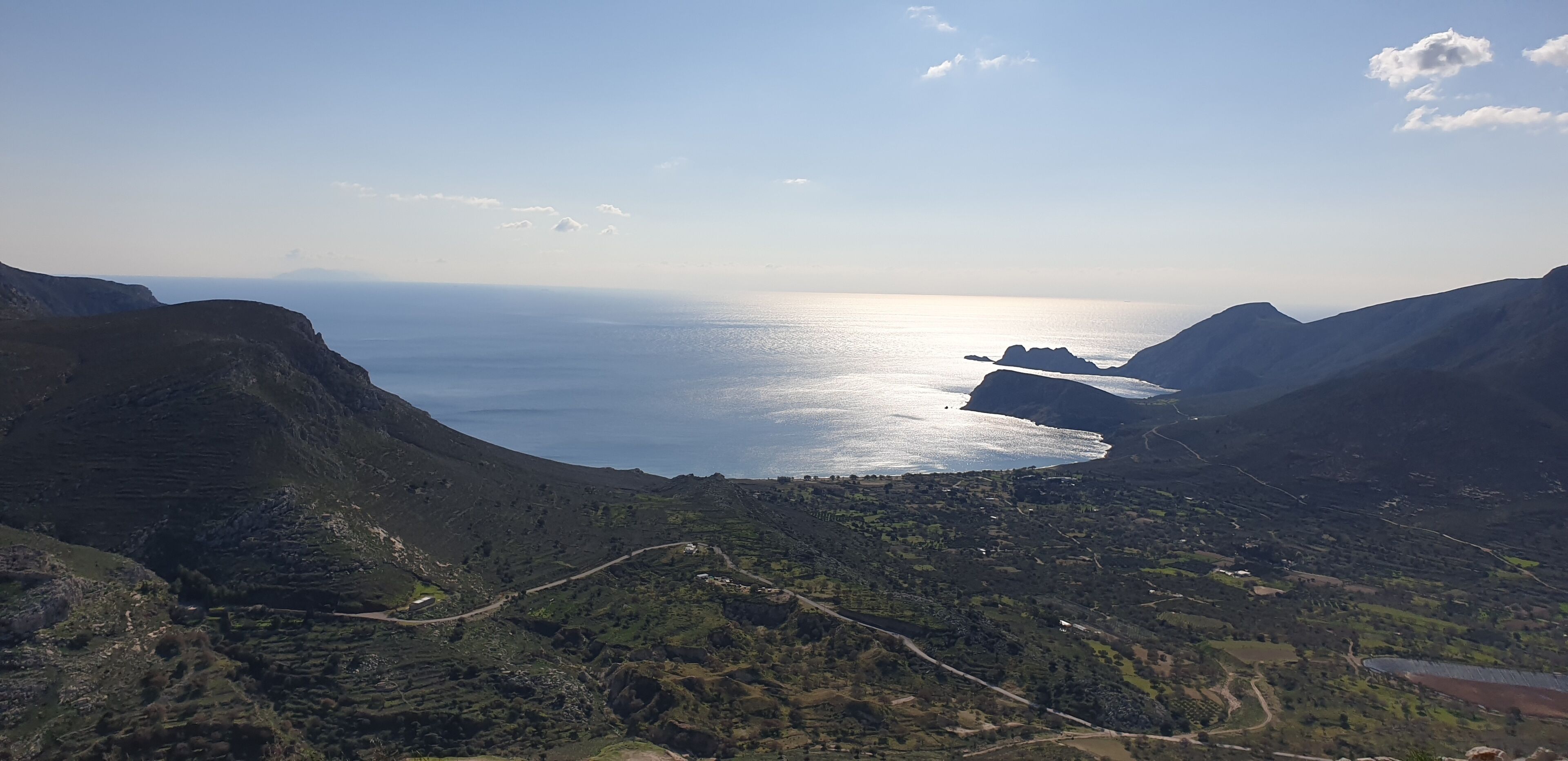 A coastal landscape with mountainous terrain and a clear view of the sea.