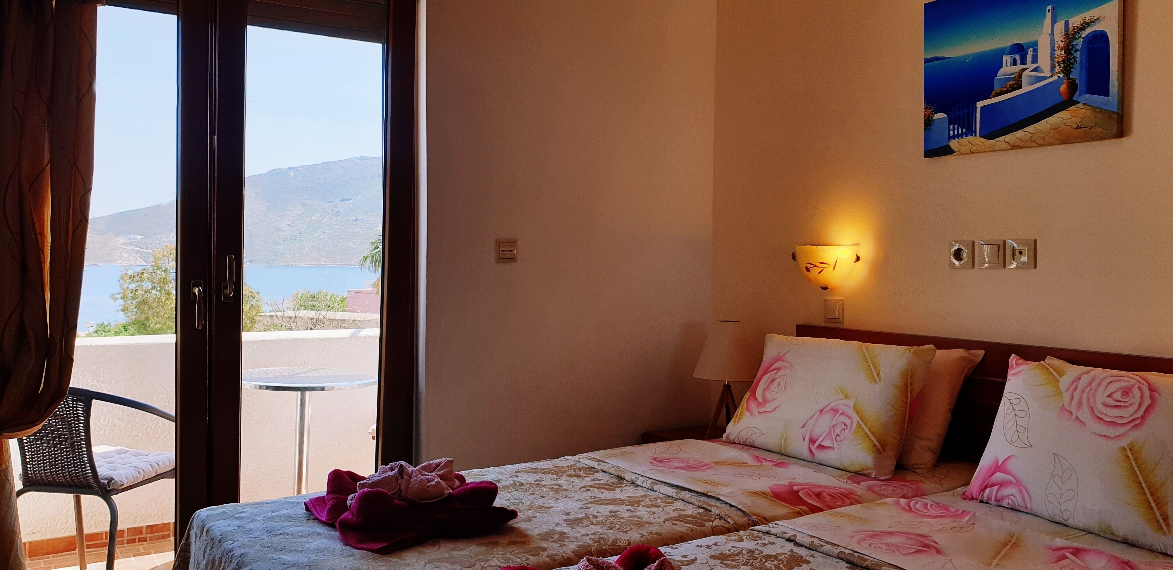 Habitación de hotel con cama, una silla, un cuadro y vista al mar.