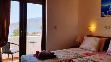 Habitación de hotel con cama, una silla, un cuadro y vista al mar.