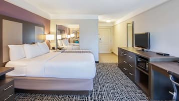 Una habitación de hotel con una cama grande, un escritorio con televisor y un espejo.