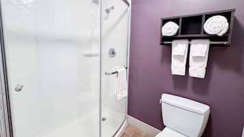A bathroom with a glass-enclosed shower, a white toilet, and a purple wall.