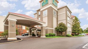 A La Quinta Inn & Suites hotel with a covered entrance, multiple floors, and a red-tiled roof.