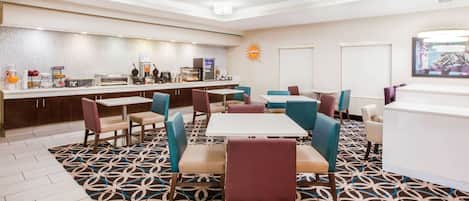 Una hall d'albergo con reception, angolo caffè e zone relax con tappeto decorato e sedie moderne.