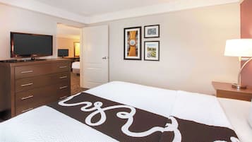 A hotel room with a bed, a TV, a dresser, and framed pictures on the wall.