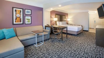A hotel room with a sofa, a desk, a bed, and a TV.