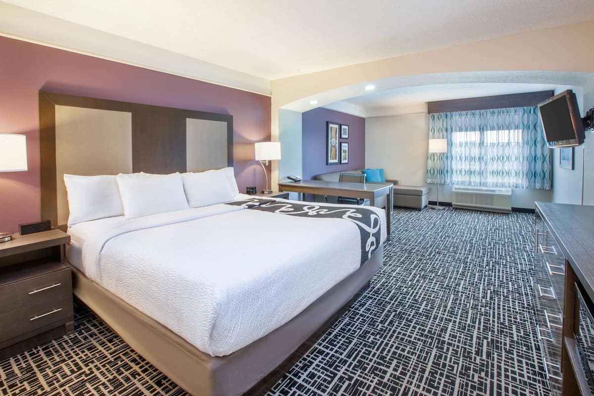 A hotel room with a large bed, a desk, a chair, and a television.