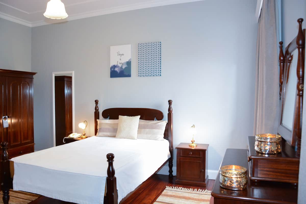 Un dormitorio ordenado con una cama grande, mesitas de noche, un armario y un cuadro en la pared.