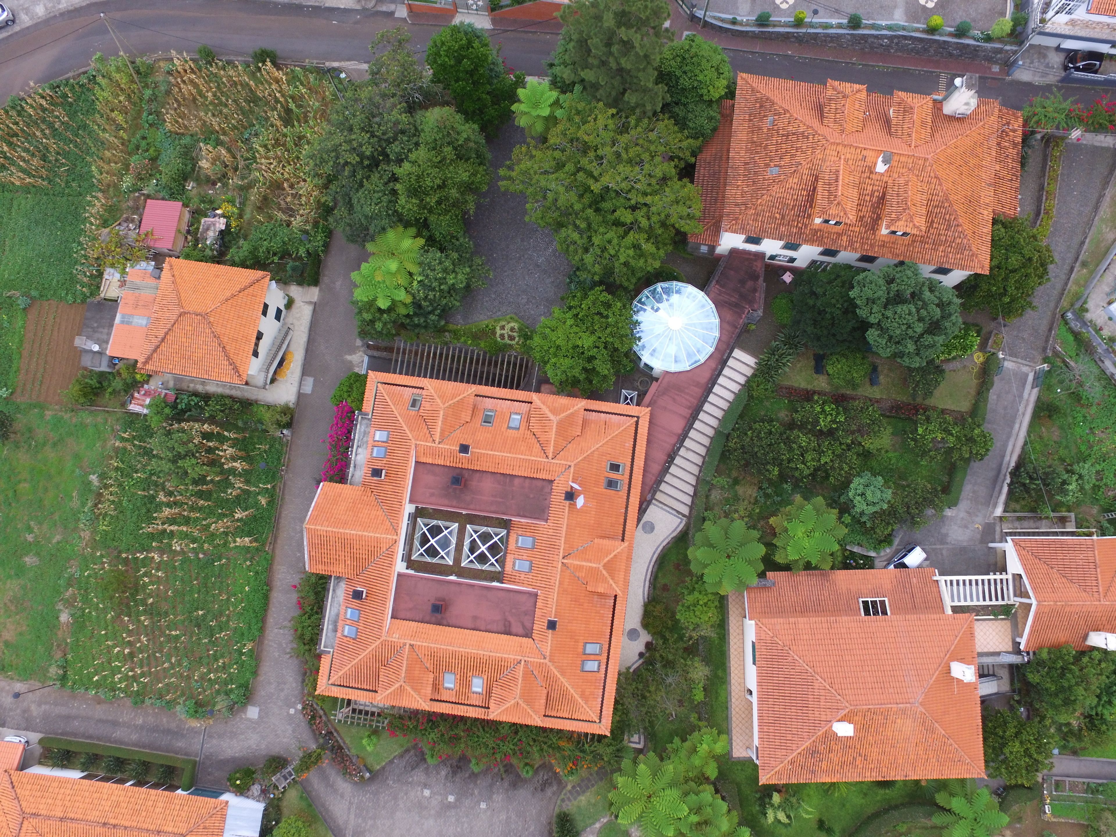 An aerial view of a residential area with multiple houses featuring red-tiled roofs and a central circular structure.