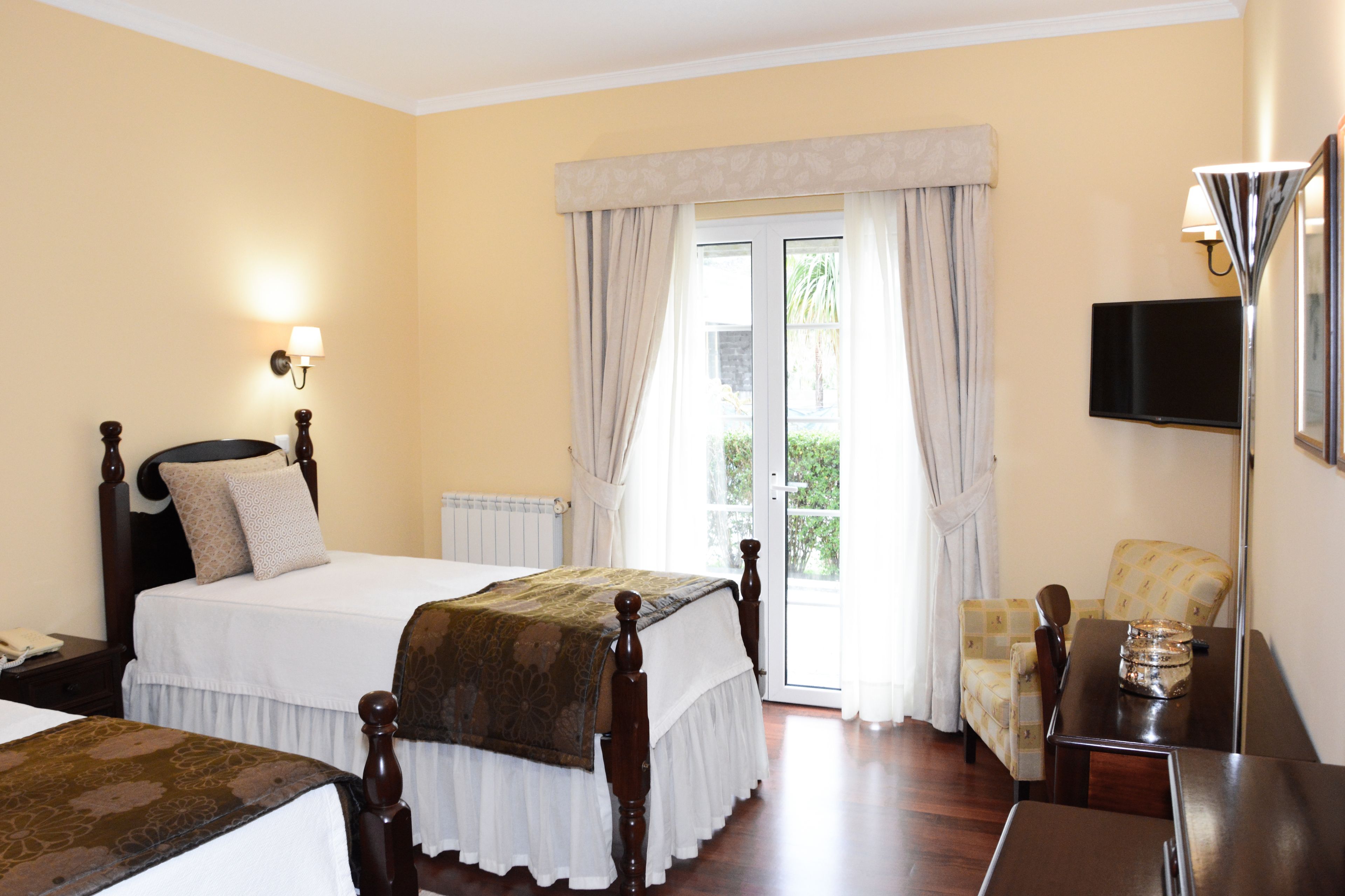 Een hotelkamer met een groot bed, een televisie, een bureau en een stoel.