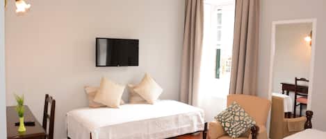 Een hotelkamer met een bed, een stoel, een televisie en een raam met gordijnen.